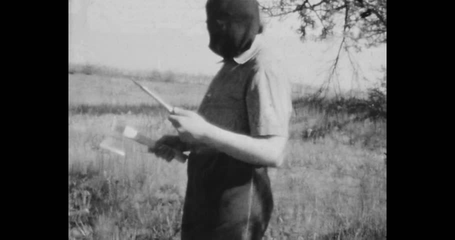Executioner in a mask with an ax and a knife in his hand is training to throw a knife. Archive, film, home cinema 1970s, Russia
