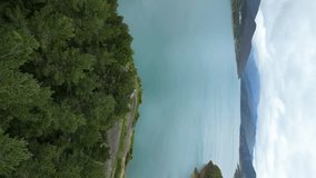 Vertical Aerial Drone Shot of Riaño Lake in Picos de Europa, Spain, with Cloudy Skies, Calm Blue Waters, Mountain Cliffs, and Lush Green Trees