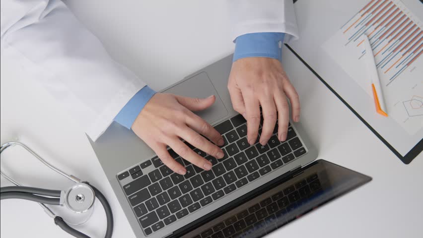 A specialist in the field medicine works with electronic prescriptions and documents. A doctor concentrates on working at desk, using technology, working on laptop. Hands typing on keyboard top view Royalty-Free Stock Footage #3428179041