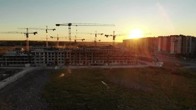 Silhouettes of construction cranes at sunset. Drone video.