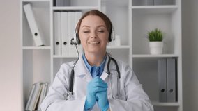 A woman, working professionally in the medical field, conducts online consultations and talks about health through a webcam on headset with headphones and microphone. Psychotherapist and psychologist