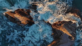 Aerial top view of waves and rocks in the sea. Vertical video
