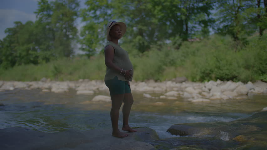 Young Pregnant Woman Relaxing in Nature at River in Motherhood Holiday