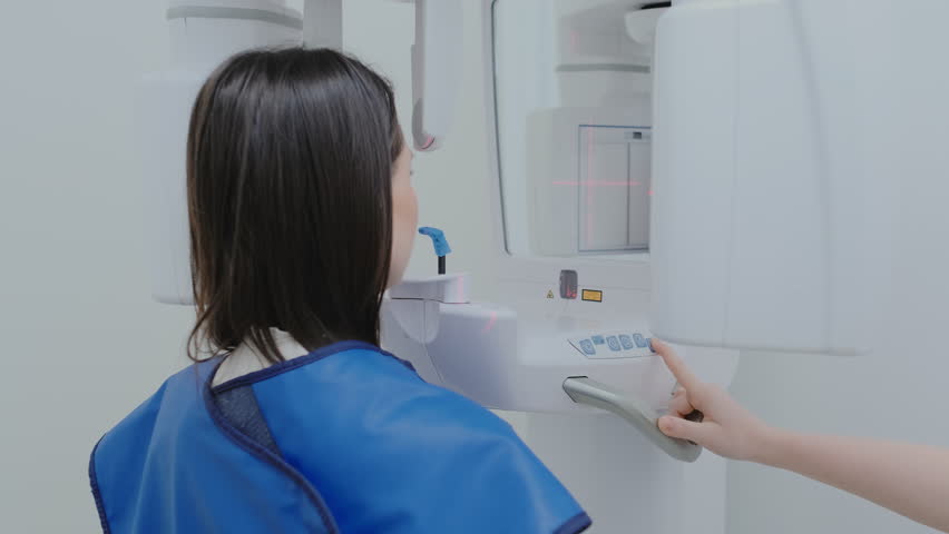 Dentist tests settings before using dental X-ray machine in private clinic. Modern dental X-ray equipment to take images of patient teeth and jaw