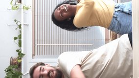 Vertical video. Multiethnic heterosexual smiling young couple dancing in kitchen. Domestic life 