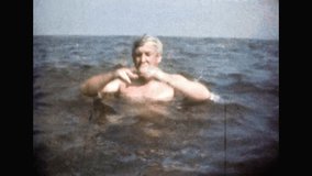 Funny man have fun, swimming in sea water. Adult person joking in ocean summer vacation. Silly man play fool. Holiday joy. Joyful recreation in travel. Archival retro film. Archive old movies 1980s