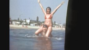 Happy man, woman playing in sea on sandy beach background. Fun games on summer sunny vacation. Funny couple together jump, dive, throw into water at holiday. Old archival film. Archive travel. 1980s - Powered by Shutterstock - Get 15% off with code: PIKWIZARD15