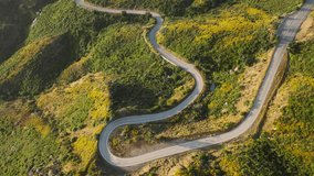 Overhead shot of curved road in green Malibu mountains, California, USA. Drone view of empty Kanan road in Santa Monica mountains. Long highway with picturesque landscape. Travel concept, 4k footage