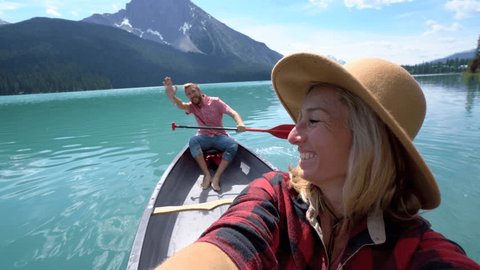 Young couple canoeing on a beautiful lake in Canada, taking selfies.
Selfie portrait of couple canoeing on Emerald lake, Canada