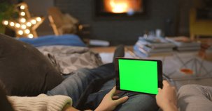 Hands, tablet and couple on green screen in home living room, social media or mockup space. Closeup, technology or people with chroma key on sofa to relax, watch advertising video or marketing on app