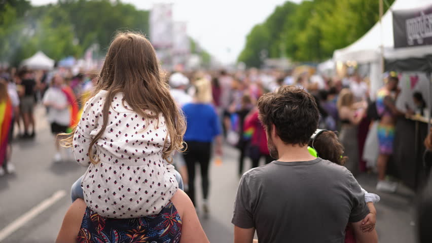 Little kid sit mother shoulders. Happy heterosexual family support lgbt community. Joy straight parents with two children have fun gay pride parade. Usual people among homosexual crowd. Queer culture. Royalty-Free Stock Footage #3428666325