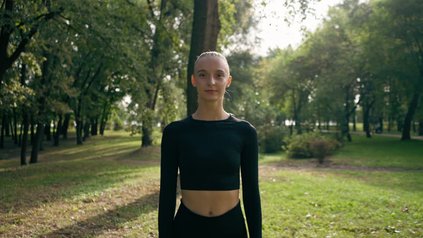 portrait of a young beautiful girl in sportswear in city park before the start of sports training