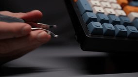 Close-up hands of unrecognizable man using special clip takes out USB receiver to connect keyboard wirelessly. Male PC user prepping new mechanical gaming RGB keyboard with stylish keycaps ready to go