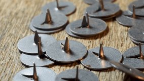 Many metal pushpins lie on the surface, close-up