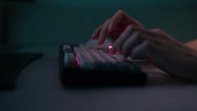 Closeup side view of unrecognizable hacker male typing on wireless RGB mechanical keyboard with colorful keycaps with ASMR sounds, sitting at desk in dark room. Shooting in slow motion. - Powered by Shutterstock - Get 15% off with code: PIKWIZARD15