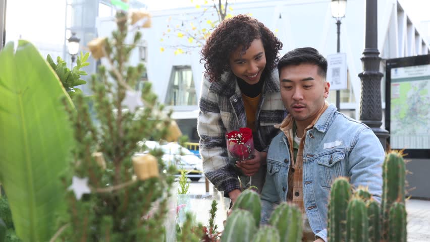 Smiling multiethnic couple buying a bouquet of red roses for Valentine