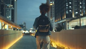 Young African American woman walking in the city at night and looking at illuminated street night lights - Powered by Shutterstock - Get 15% off with code: PIKWIZARD15