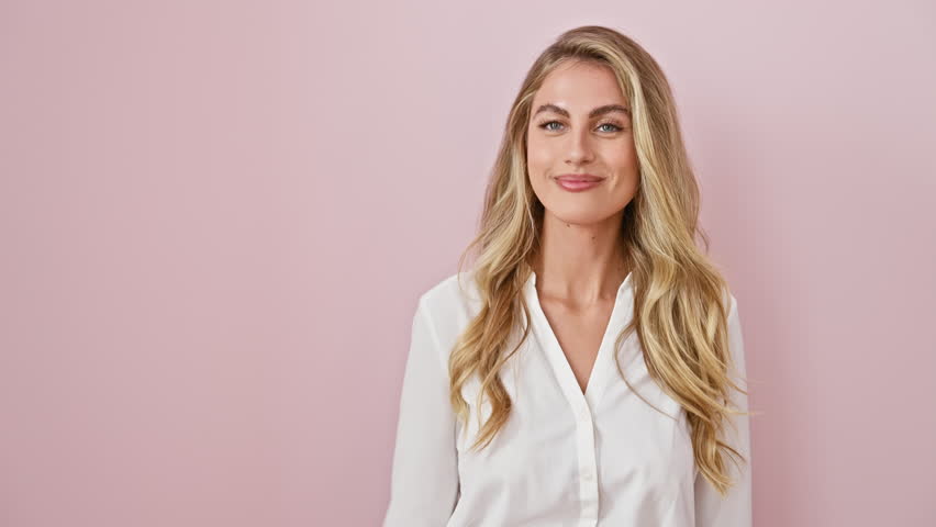 Cheery young blonde points to the side! snappy shirt-clad woman smiling at camera on a snazzy pink wall. Royalty-Free Stock Footage #3428952339