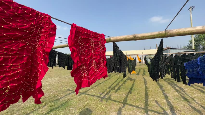 Hand-dyed fabrics drying in the wind in Madhabdi, Bangladesh.