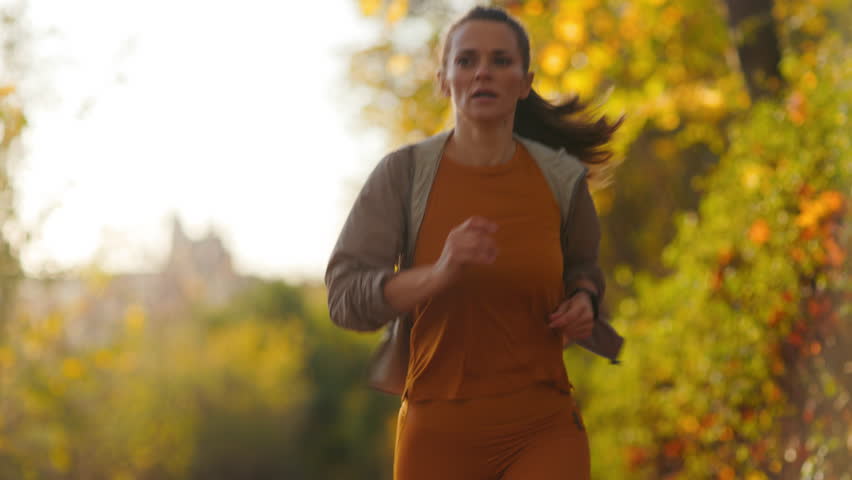 Hello autumn. Full length portrait of elegant woman in fitness clothes in the park running.