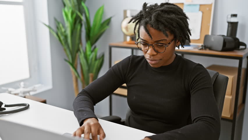 Surprised young black woman with dreadlocks in the office, skeptically working on laptop, shocked expression, sarcastically open-mouthed. Royalty-Free Stock Footage #3429011849