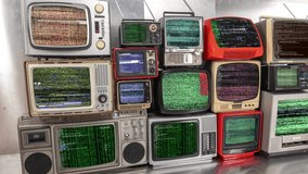 Amazing collection of vintage and retro televisions made into a tv wall with streaming code and data on the screen