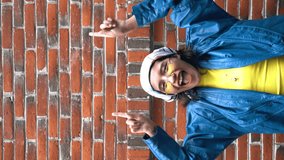 4k vertical video young woman mexican dressed with a yellow t-shirt, a blue jacket is pointing up an empty space for text. Advertisement