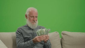 Green Screen. A Rich Old Man with a Gray Beard Counting His Money in US Dollars. An Elderly Man is Satisfied by the Amount of US Dollar Money in His Hands. Saving for Retirement.