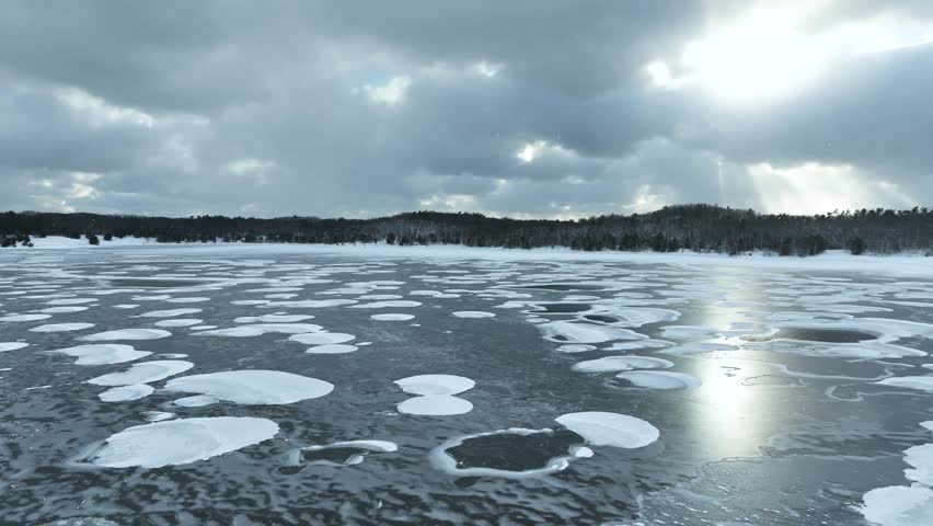Reverse track over a frozen lake with gorgeous cloud cover and light.