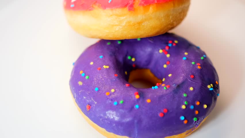 Donuts covered with lilac and pink glaze rotate in a circle on a white background