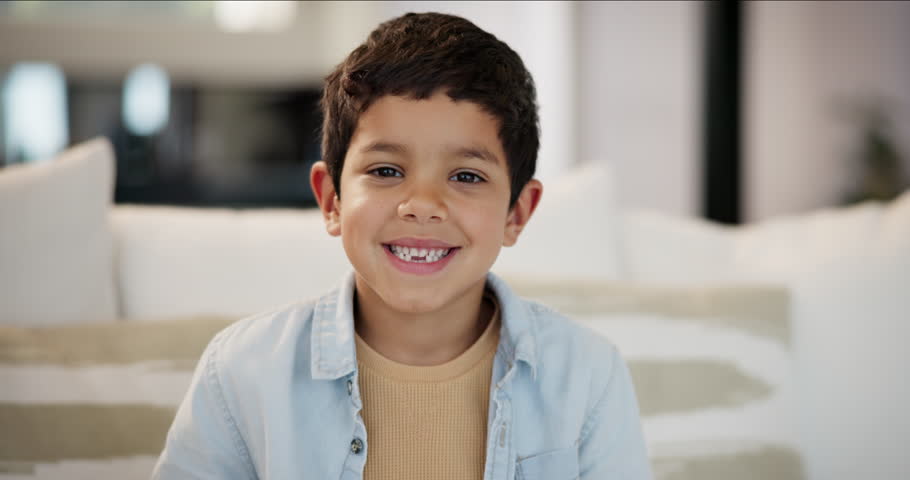 Face, smile and boy child in home, sitting on sofa in living room to relax on weekend with free time. Portrait, kids and break with happy or cute youth in apartment for growth, rest or development