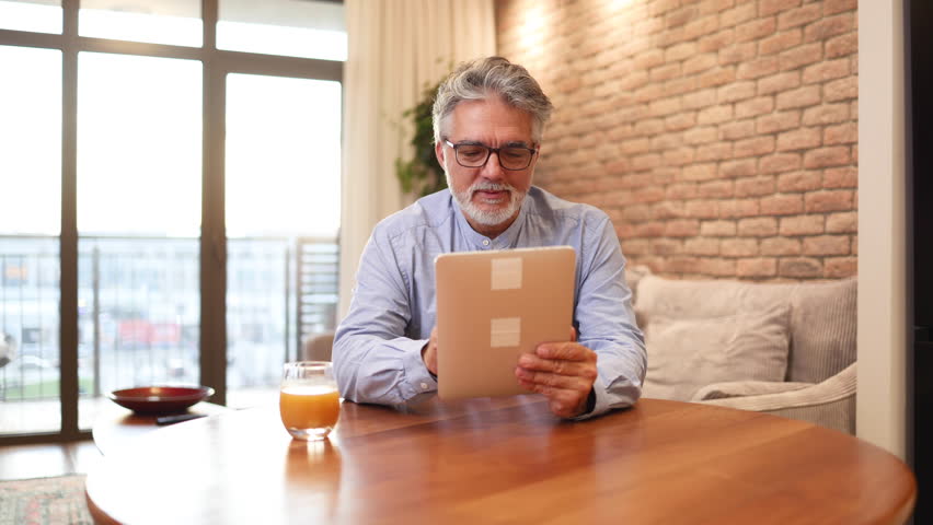 Mature man enjoying at home and using a digital tablet Royalty-Free Stock Footage #3429250531