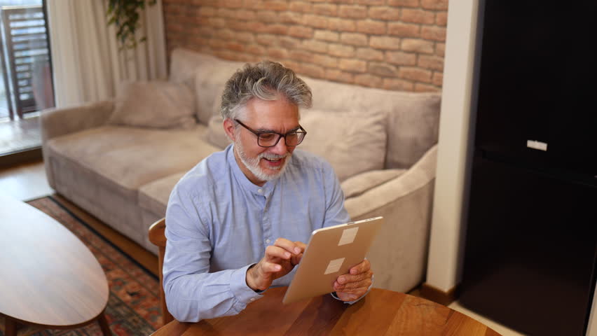 Mature man having fun online on a tablet Royalty-Free Stock Footage #3429279893