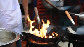 Fire burning in the pan on the stove while preparing to cook food at the market. Chef stir fry in wok. - Powered by Shutterstock - Get 15% off with code: PIKWIZARD15