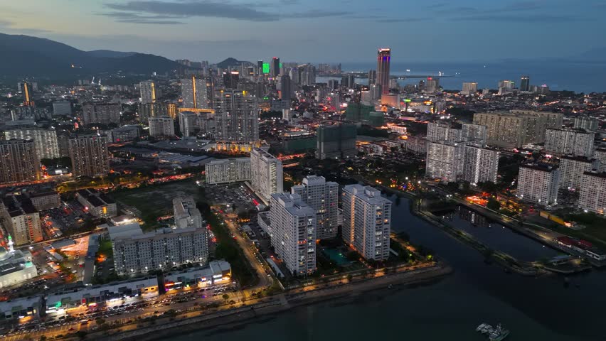 Aerial evening shot of George Town, Penang, Malaysia. Embankment and city center with skyscrapers and illumination after sunset in GeorgeTown, Penang