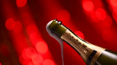 Champagne explosion, popping over red blinking background, opening champagne bottle closeup. Sparkling Wine Background. Champagne bottle closeup. Success, holiday, wedding celebrating. Slowmo. UHD 4K