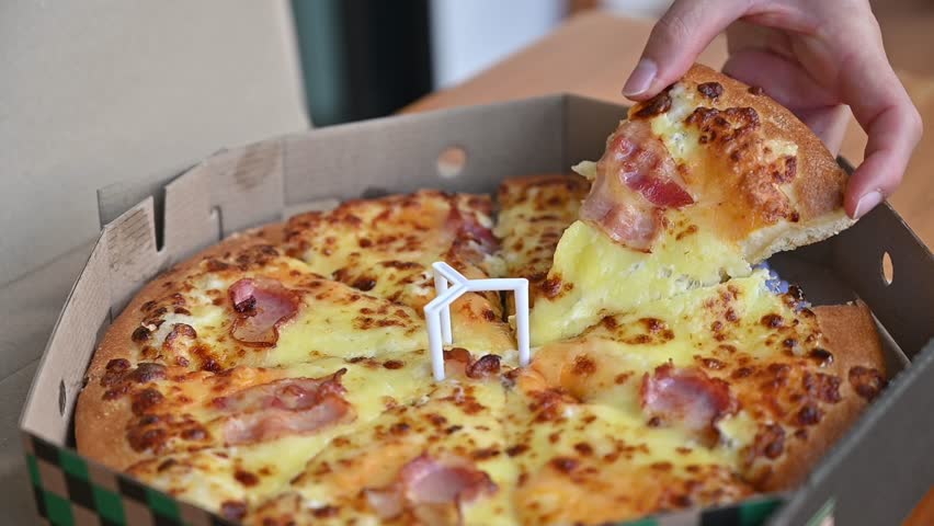 Someone hand grabbing a piece of cheese pizza before eating. Pizza is a favorite food for many around the world.