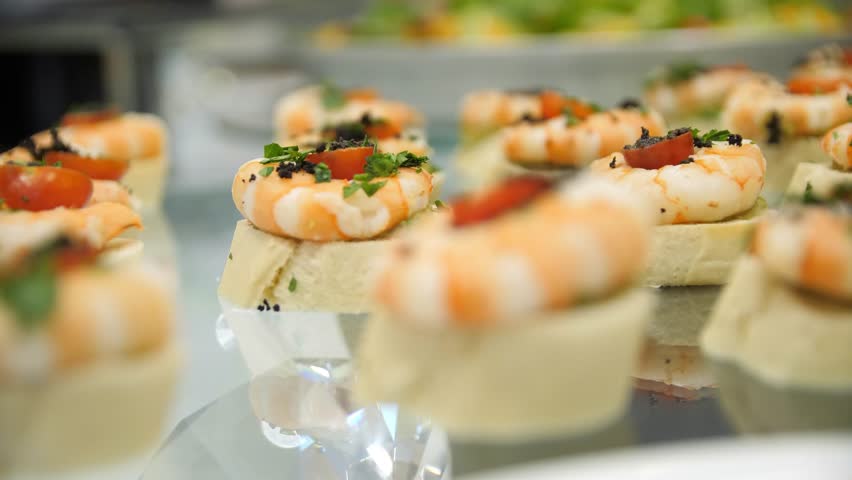 Close-up of canapes with shrimps, cherry tomatoes and herbs on a buffet table in a restaurant. Close-up of buffet food .	 Royalty-Free Stock Footage #3429568355