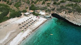 Aerial drone video from iconic sandy beach of Andros with sun beds and umbrellas, Cyclades, Greece