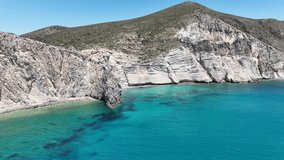Aerial drone video of beautiful turquoise beach and cave formations visited by yachts and sailboats in Southern part of Antiparos island, Cyclades, Greece