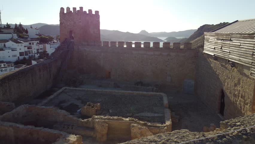 Aerial drone view of the castle of Iznajar with the reservoir in the background at sunset.