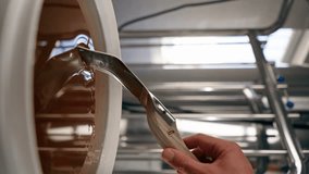 vertical video close-up a hand with a special metal spoon collects and stirs natural liquid honey which flows back into large bowl
