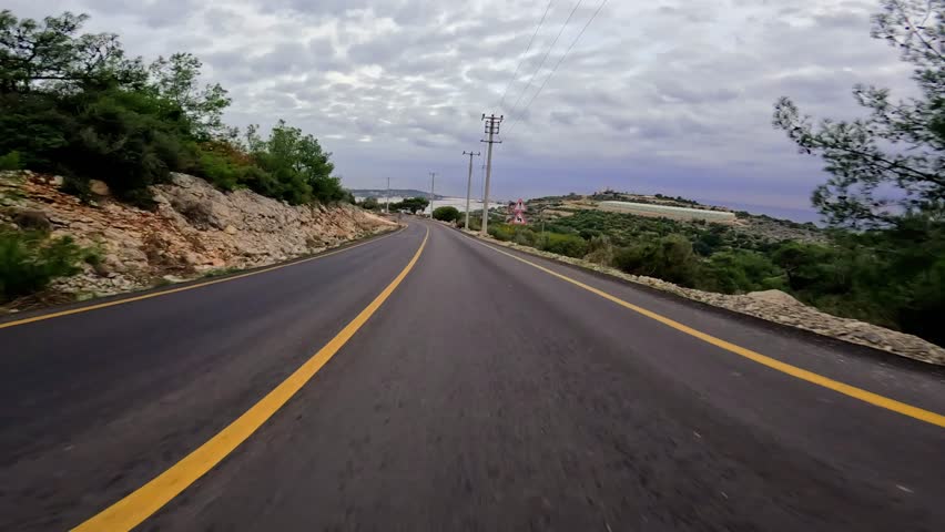 Car takes turns on mountain asphalt road, scenic drive. Sharp turn on asphalt road in mountains, clear blue sky. Asphalt road journey, turning paths in mountainous terrain