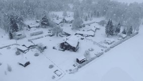 Scenic slow fly video around small Scandinavian village during heavy snowfall. Extreme winter conditions.