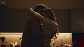 Tender lovers dancing in dark apartment kitchen closeup. Happy affectionate couple hugging moving together slowly at evening date. Young family pair celebrating anniversary with wine red roses at home - Powered by Shutterstock - Get 15% off with code: PIKWIZARD15
