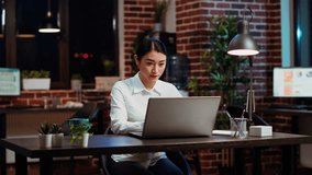 Portrait of smiling asian businesswoman doing computer tasks for team project in office. Cheerful employee working late at night, typing on laptop keyboard next to coworker, camera B - Powered by Shutterstock - Get 15% off with code: PIKWIZARD15