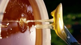 vertical video close-up of a stream of natural liquid honey flowing back into a large bowl at a mead distillery