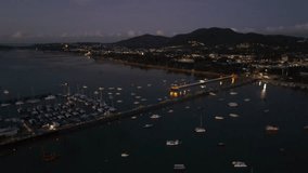 Aerial drone view of illuminated Chalong Pier at dawn in Phuket, Thailand. Many boats, yachts and speed boats moored at the pier platform of Ao Chalong Bay, one of centers to travel around Andaman Sea