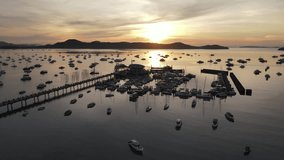 Aerial drone view of Chalong Pier during sunrise in Phuket, Thailand. Many yachts, catamaran and speed boats moored at the pier platform of Ao Chalong Bay, one of centers to travel around Andaman Sea.