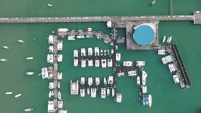 Aerial drone view of Chalong Pier in Phuket, Thailand. Many boats, yachts, sailboats and catamaran moored at the pier platform of Ao Chalong Bay, one of centers to travel around Andaman Sea.